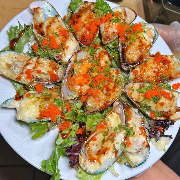 Baked mussels topped with cheese, orange tobiko, and green onions, served on a bed of lettuce.