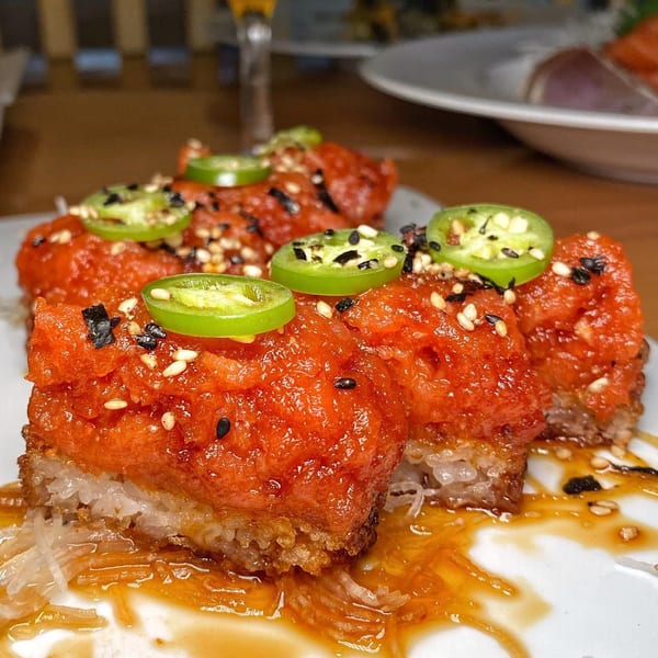 Tengoku Sushi's spicy tuna crispy rice, topped with jalapeño slices, sesame seeds, and sauce.