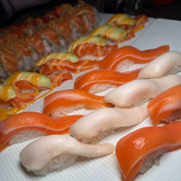 A platter of sushi with salmon nigiri, white fish nigiri, and salmon avocado rolls.